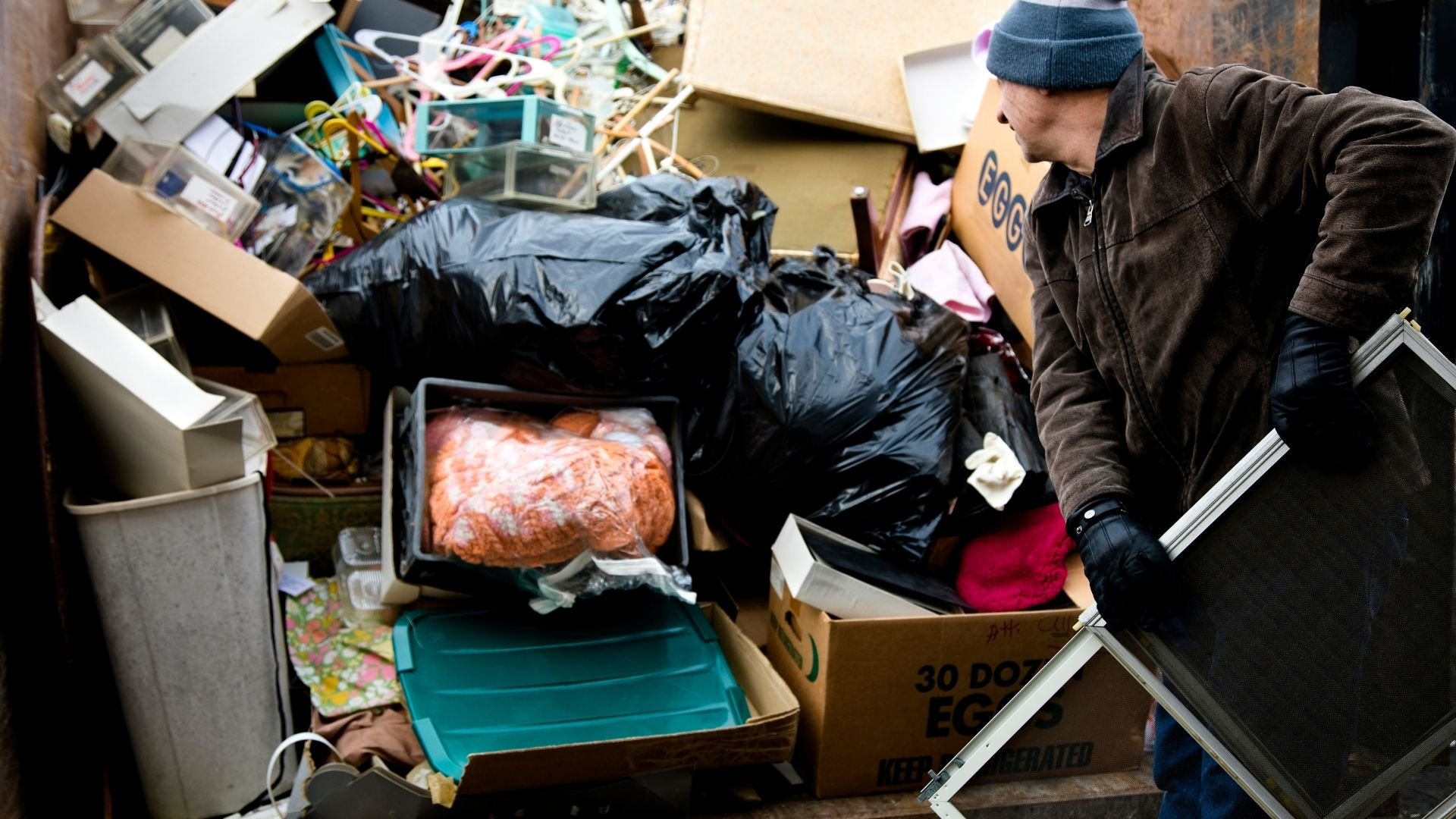 Person sorting through cluttered boxes of items and belongings during cleanup or donation process.