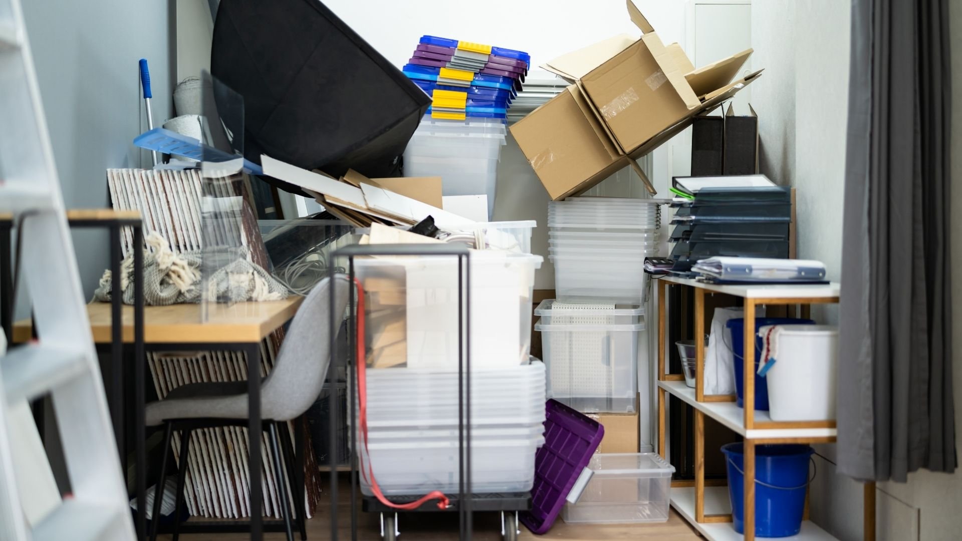 Cluttered storage room with stacked boxes, files, and office supplies