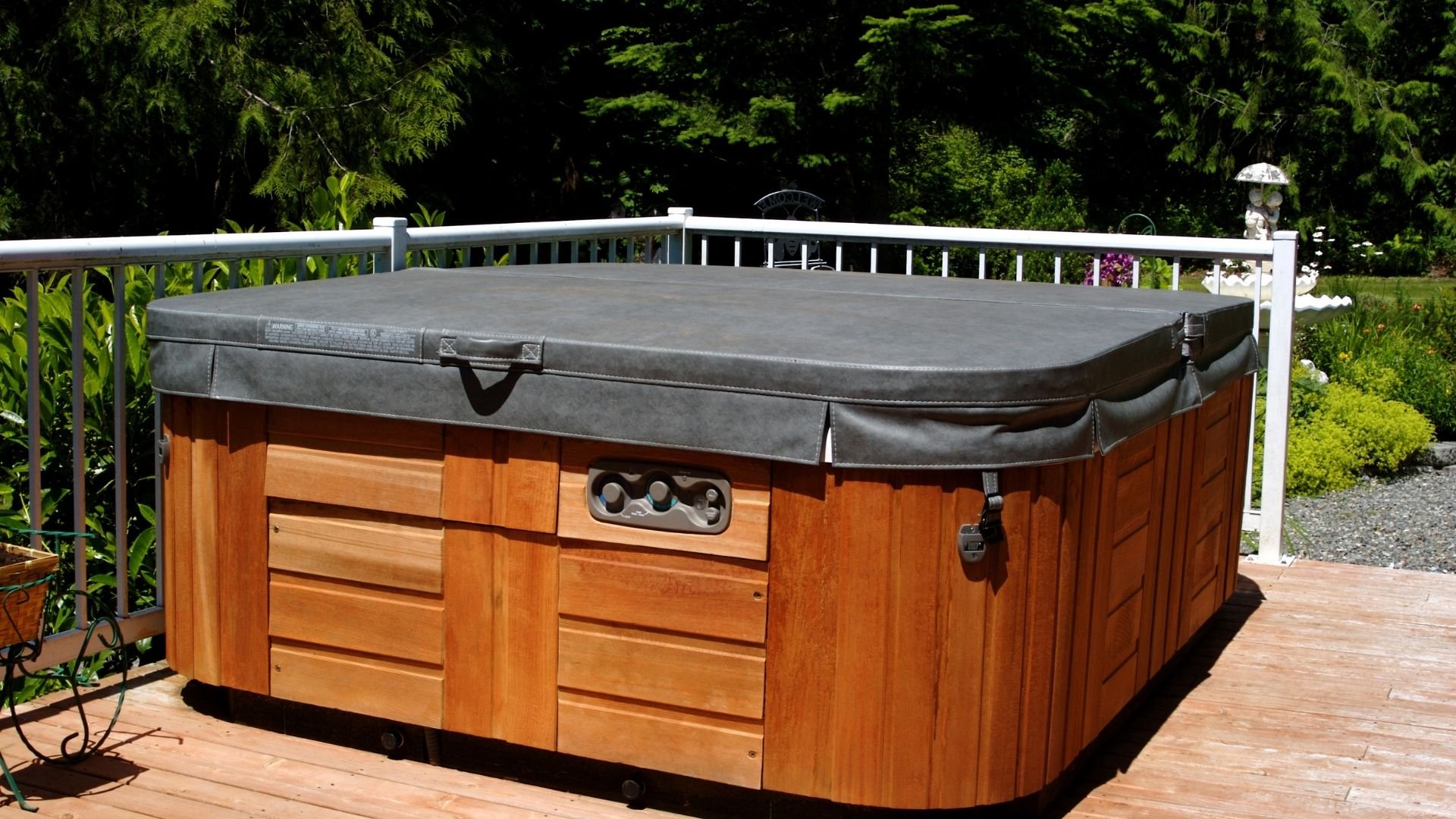 Hot tub with wooden exterior and dark cover on a sunny residential deck