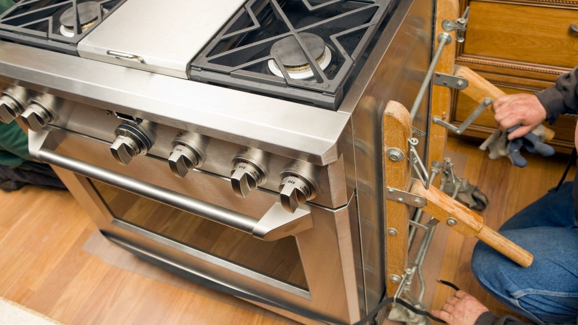 Stainless steel gas range with gas burners and wooden cabinetry in kitchen